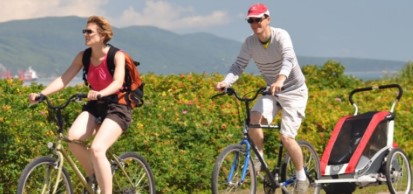 Couple faisant du vélo, l'homme tirant une carriole avec enfant derrière luit